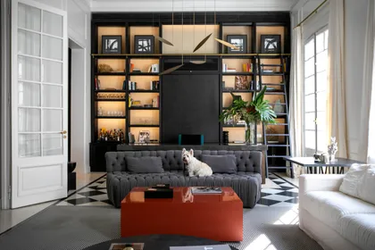 Living moderno con estanterías integradas y mesa de centro roja — proyecto ARROYO, por Parq Estudio, en Buenos Aires